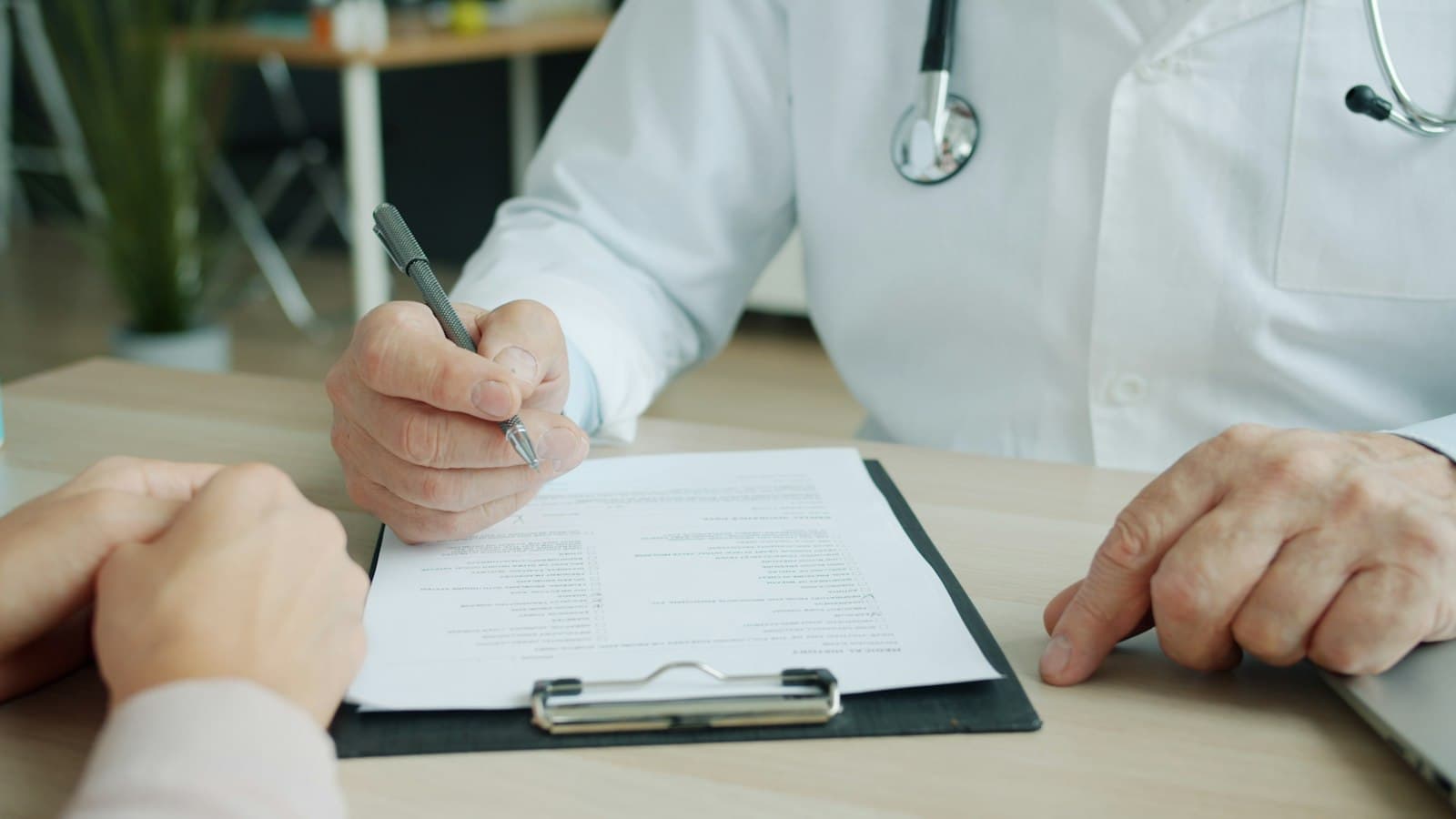 A doctor writing notes on a patient chart